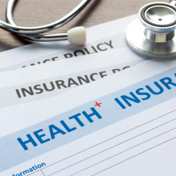 Health insurance policy paperwork with a stethoscope resting on top