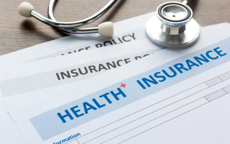 Health insurance policy paperwork with a stethoscope resting on top
